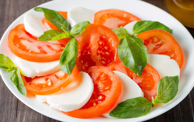 Close-up photo of caprese salad with ripe tomatoes, basil, buffalo mozzarella cheese. Italian and Mediterranean food concept. Fresh and healthy organic meal. Starter and antipasti. 