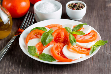 Close-up photo of caprese salad with ripe tomatoes, basil, buffalo mozzarella cheese. Italian and Mediterranean food concept. Fresh and healthy organic meal. Starter and antipasti. 