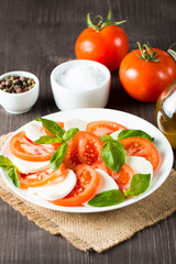 Close-up photo of caprese salad with ripe tomatoes, basil, buffalo mozzarella cheese. Italian and Mediterranean food concept. Fresh and healthy organic meal. Starter and antipasti. 
