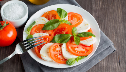 Close-up photo of caprese salad with ripe tomatoes, basil, buffalo mozzarella cheese. Italian and Mediterranean food concept. Fresh and healthy organic meal. Starter and antipasti. 
