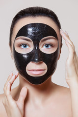 a black mask to the face of a beautiful woman. Spa treatments and care of the cats in the beauty salon.