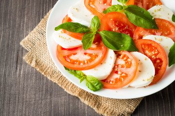 Close-up photo of caprese salad with ripe tomatoes, basil, buffalo mozzarella cheese. Italian and Mediterranean food concept. Fresh and healthy organic meal. Starter and antipasti. 