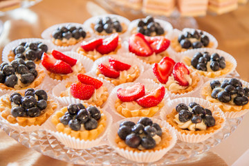 Tart-lets with whipped cream and strawberries and blueberries on cake stand for a party