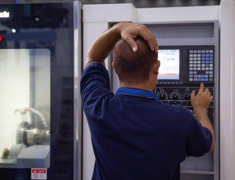 Industrial professional feeling stress at work during input data to programming CNC turning center machine. Industrial manufacturing
