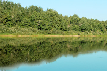 The green forest is mirrored in the water