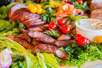 Homemade lard, sausage and cold cuts, some bread, decorated with lettuce and cherry tomatoes