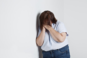 femme ronde pleurant contre un mur