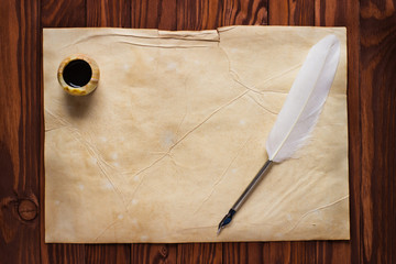 Inkwell and white feather on a background of the empty form for letter
