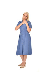 full length portrait of blonde girl wearing blue dress. standing pose. isolated on white  studio background.