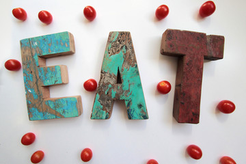 EAT wood lettering surrounded by tomatoes