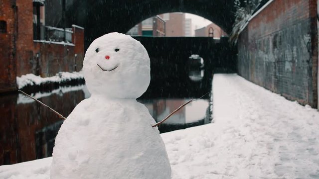Happy snowman stood canal-side in the snow