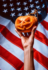 pumpkin halloween in hand against the background of the American flag