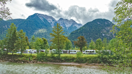Sommer Campingplatz in den Bergen mit Wohnwagen und Zelten an einem Fluß - obrazy, fototapety, plakaty