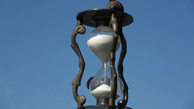 Rotating retro hourglass  with two snails on sky background

