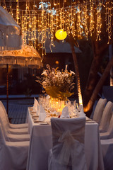 Wedding Banquet or gala dinner decorated with garlands. Festive Luxury table set up decor for...