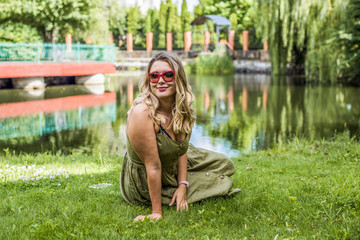 A woman of plus size, American or European appearance walks at park enjoying life. A middle age lady with excess weight, in a stylish dress 