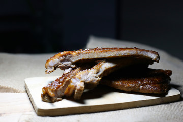 Closeup baby pork ribs spare with barbecue sauce on wood plate. Homemade baked spareribs sliced. 