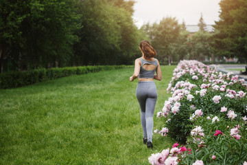 A brunette runner woman runs in the park jogging.