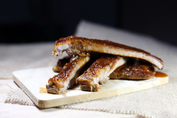 Closeup baby pork ribs spare with barbecue sauce on wood plate. Homemade baked spareribs sliced. 