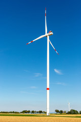 Wind turbine generating electricity on a bright blue sky.