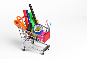 Shopping cart with school supplies on white background