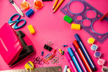 Felt pens, pencils, clips of different colors on a pink background