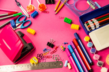 Felt pens, pencils, clips of different colors on a pink background