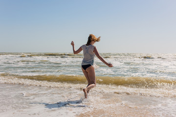 Fototapeta na wymiar Happy playful female dance on seaside during day.