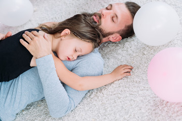 parenting lifestyle. tired exhausted father fell asleep hugging his little hyperactive daughter. fatherhood and childhood sweet moments of love and care.