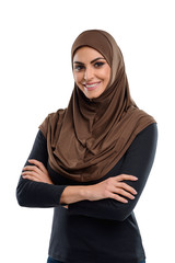 Half-length portrait of smiling Muslim girl standing with crossed arms. Simple and modest outfit including hijab.