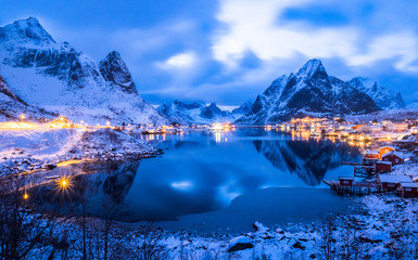 Famous tourist attraction Reine on Lofoten Islands, Norway, in twilight winter season, the village is covered with snow.