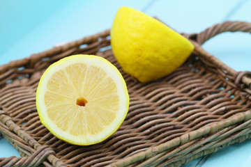Two halves of ripe lemon on wicker tray
