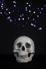 Minimal white plaster skull on blurry blue cross light bokeh background