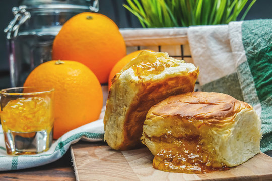 Orange jam in toast bread and orange fruit on over wooden table