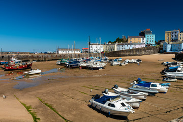 Fototapeta na wymiar Colorful fishing and pleasure boats resting on the sand at a harbor during low tide on a sunny day