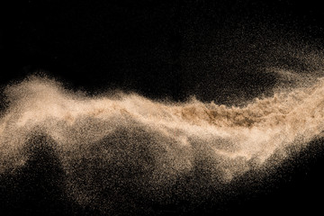 Dry river sand with stone explosion. Golden colored sand splash agianst dark background.