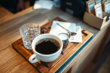 Cup of fresh black coffee, milk and glass of water