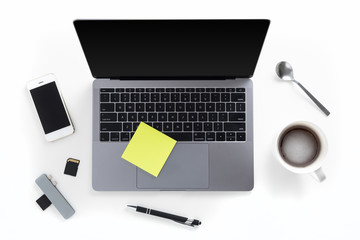 Top view of tabletop with laptop, mobile phone, memory cards, card reader, pen, coffee cup, spoon and post it notes