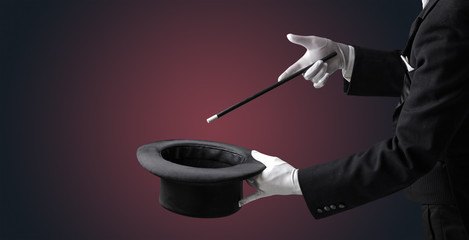 Illusionist white hand wants to conjure with magic wand from a black cylinder something