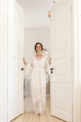 silhouette of young beautiful girl bride in a peignoir  stands in the doorway of the bedroom and waiting for the groom