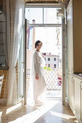 silhouette of young beautiful girl bride in a peignoir  stands in the doorway of the balcony overlooking the old city and waiting for the groom