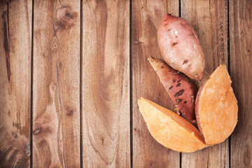 Sweet potatoes on a wooden background, free space for text
