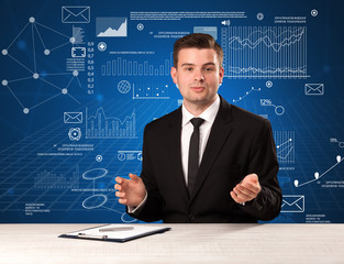Young handsome businessman sitting at a desk with blue charts and data behind him