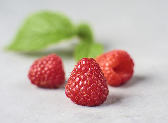 Fresh and ripe raspberry  with green leaves on concrete background