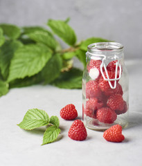 Fresh and ripe raspberry in glass jar on  concrete background