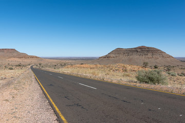 Asphalt road though arid countryside with clear blue sky, Africa