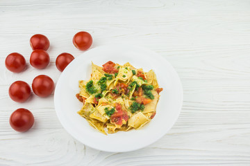 Italian pasta with tomatoes and pesto sauce, on a wooden background