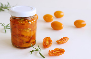 Dried tomatoes preserves with herbs in jar. White background.Food concept.