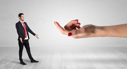 Businessman with kisses on his face in an empty space where a big hand baiting him
