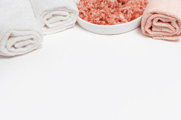 Large crystals of pink salt for bath and cotton bath rolled towels. Spa background Spa set. Copy...